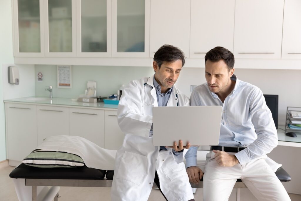 Doctor discussing testosterone replacement therapy results with a patient on a laptop during a consultation